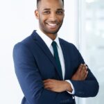 Premium Photo _ Confident corporate charm A handsome young african american businessman standing indoors with his arms folded