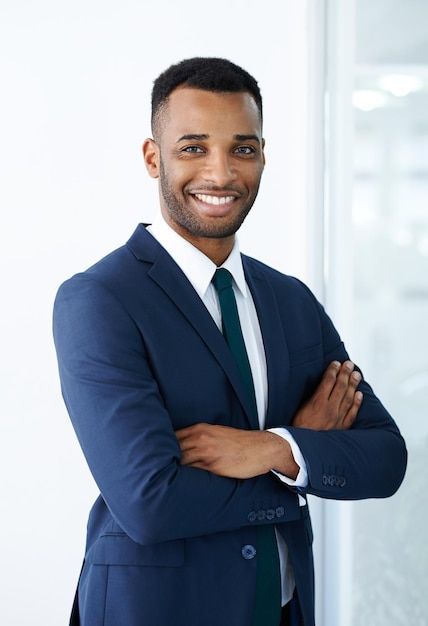 Premium Photo _ Confident corporate charm A handsome young african american businessman standing indoors with his arms folded